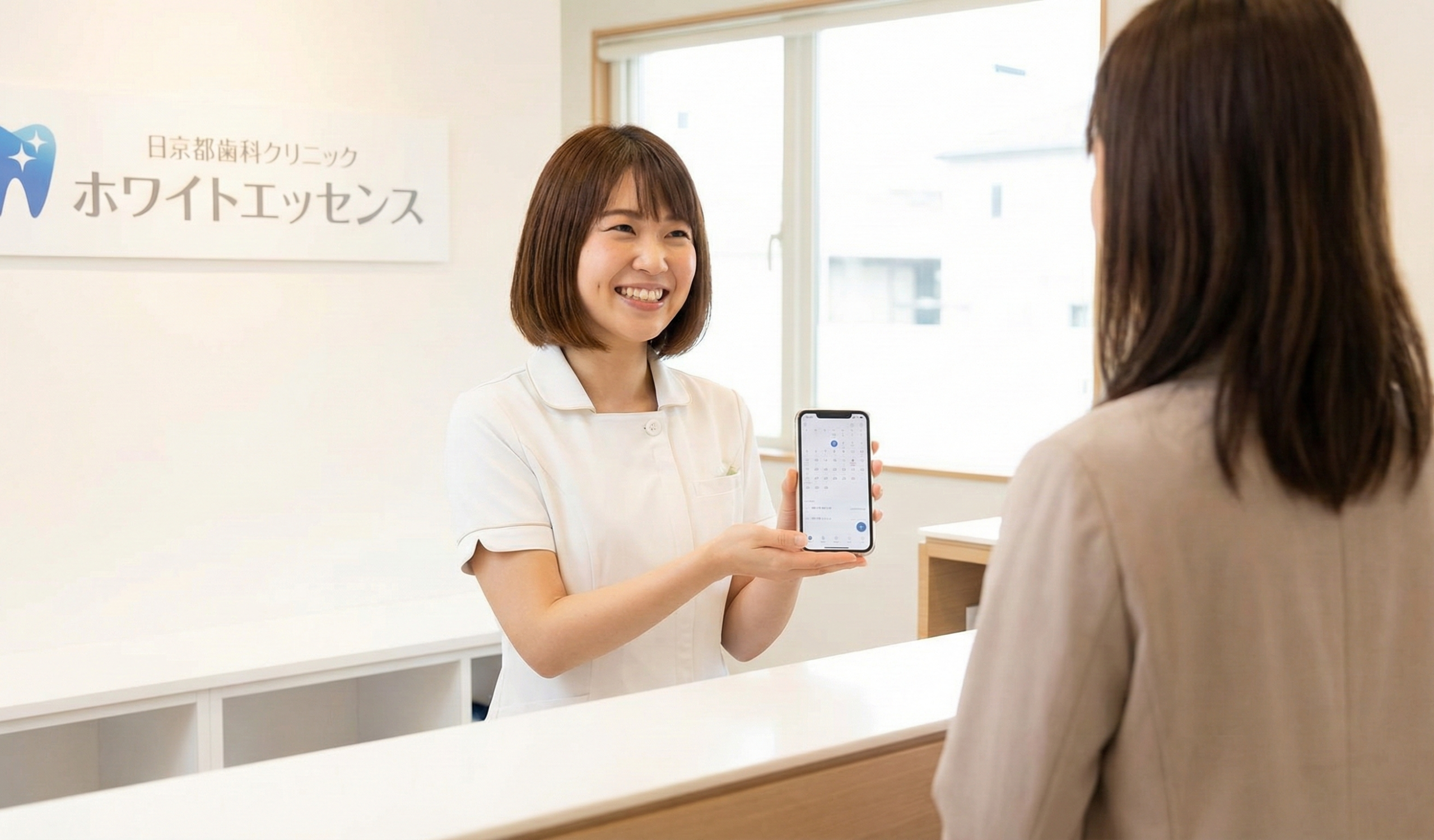 笑顔で患者を迎える歯科医院スタッフとスマートフォンのイメージ画像